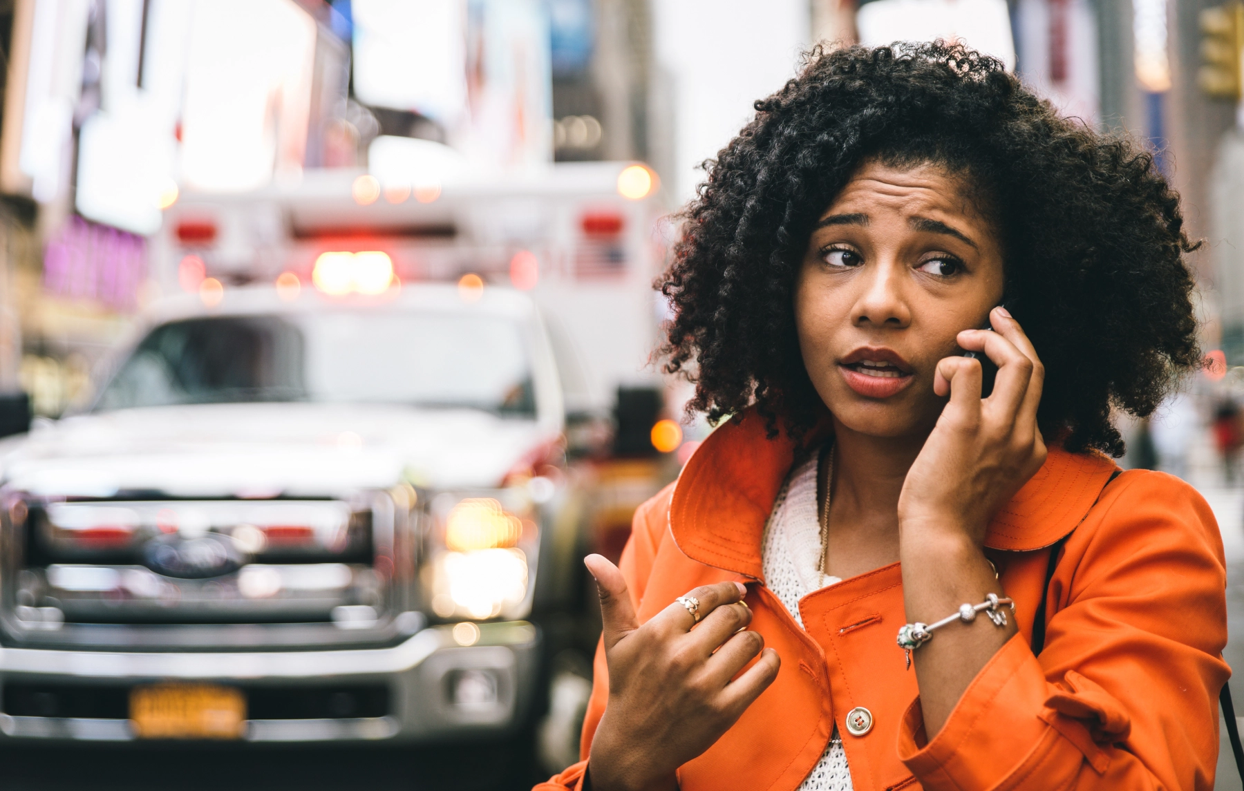 woman on her phone concerned with an ambulance behind her