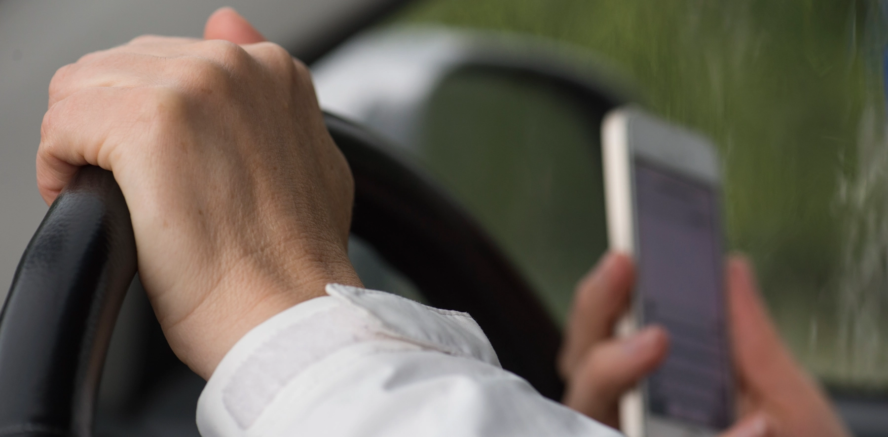 hand holding up a phone while driving